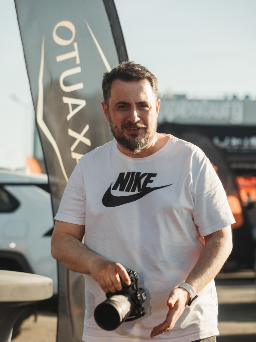 Fotograf cu aparat și teleobiectiv, pe teren la un eveniment auto